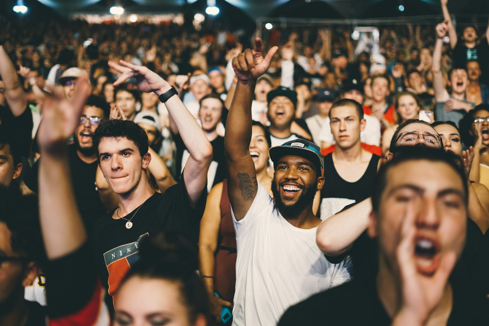 A crowd celebrating under the lights of an open-air music festival